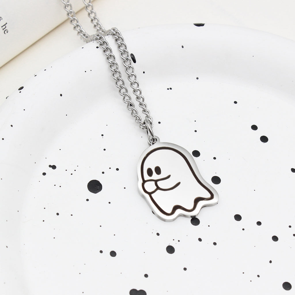 Pendentif fantôme timide sur chaîne en acier, posé sur une assiette blanche mouchetée