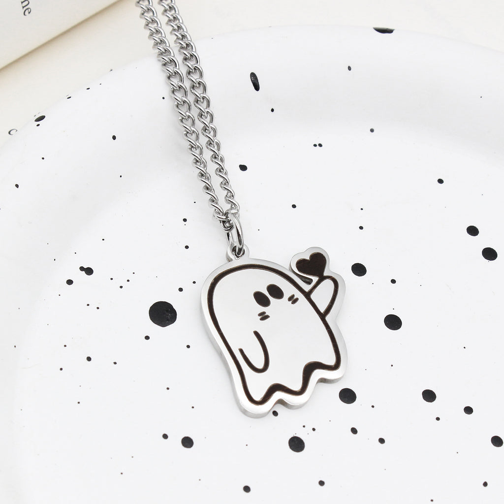 Pendentif fantôme au cœur sur chaîne en acier, posé sur une assiette blanche mouchetée
